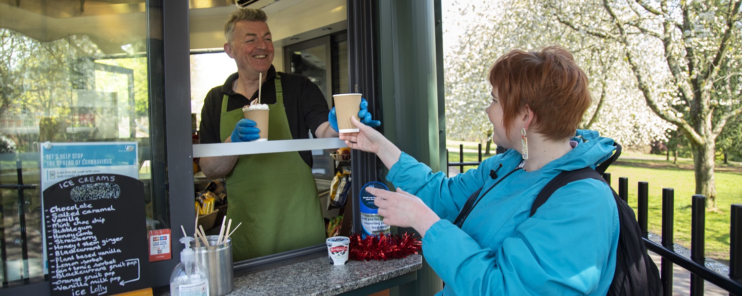 A member of staff serving a woman a hot drink
