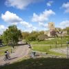 Castle Park with grassy areas and paths, cyclists and a church in the background.