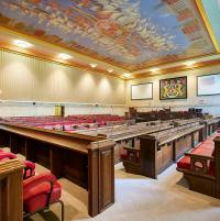 Photograph of the inside of Britsol City Council's Chamber showing rows of dark wood benches with red seats