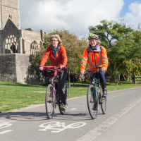 Two women in high-vis jackets cycling along the cycle path in Castle Park