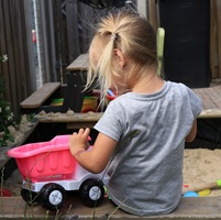 A young girl plays in a sand pit.