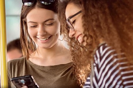 Two young women looking at a smartphone and smiling