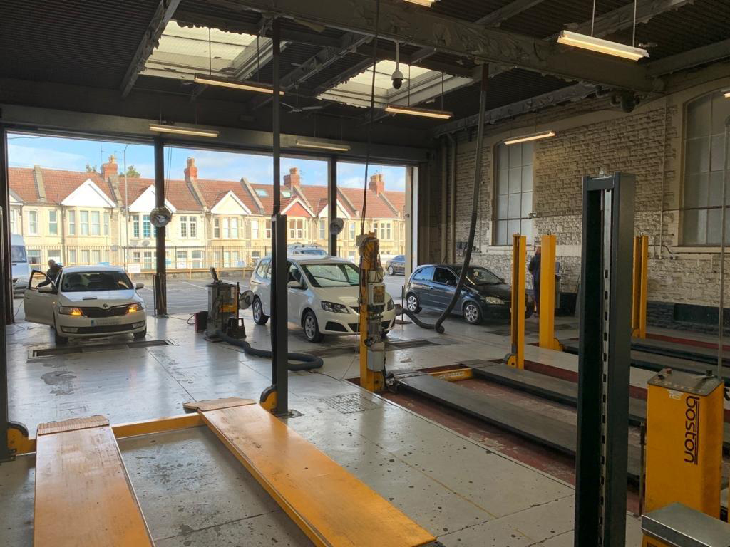 The interior of an MOT testing centre with three cars ready to be tested.