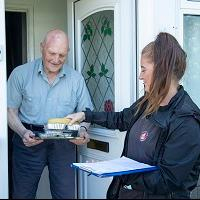 Bristol Community Meals staff member holding a hot meal in containers.