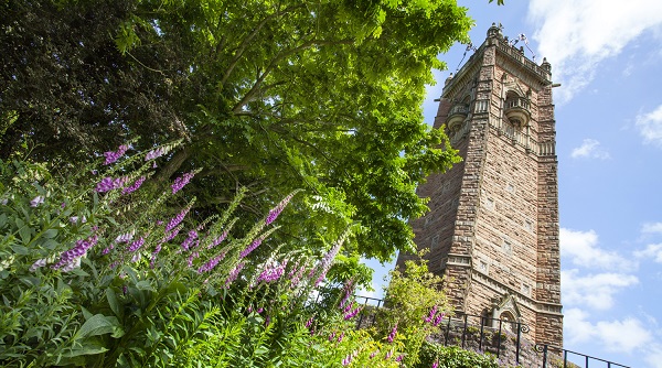 An old tower surrounded by green plants and flowers