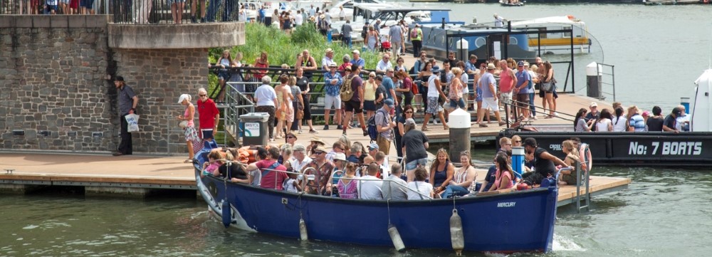 Lots of people on a boat and on the shore in summertime