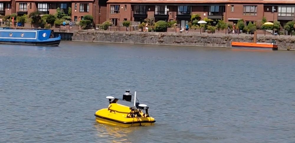 yellow robot on the water, some boats in the background
