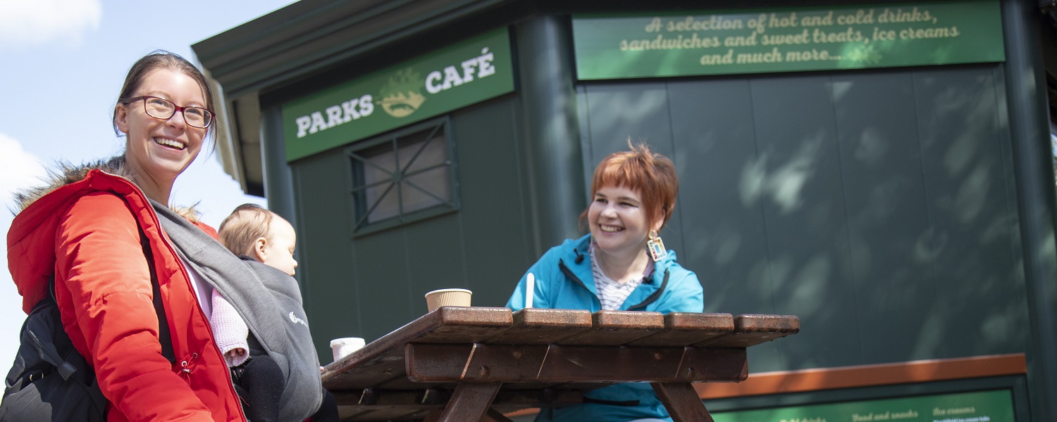 Two women and a baby enjoying drinks in the cafe's outside seating area