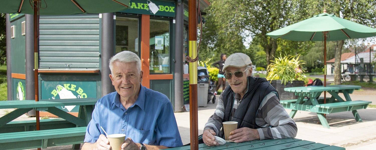 Two men enjoying drinks outside a cafe