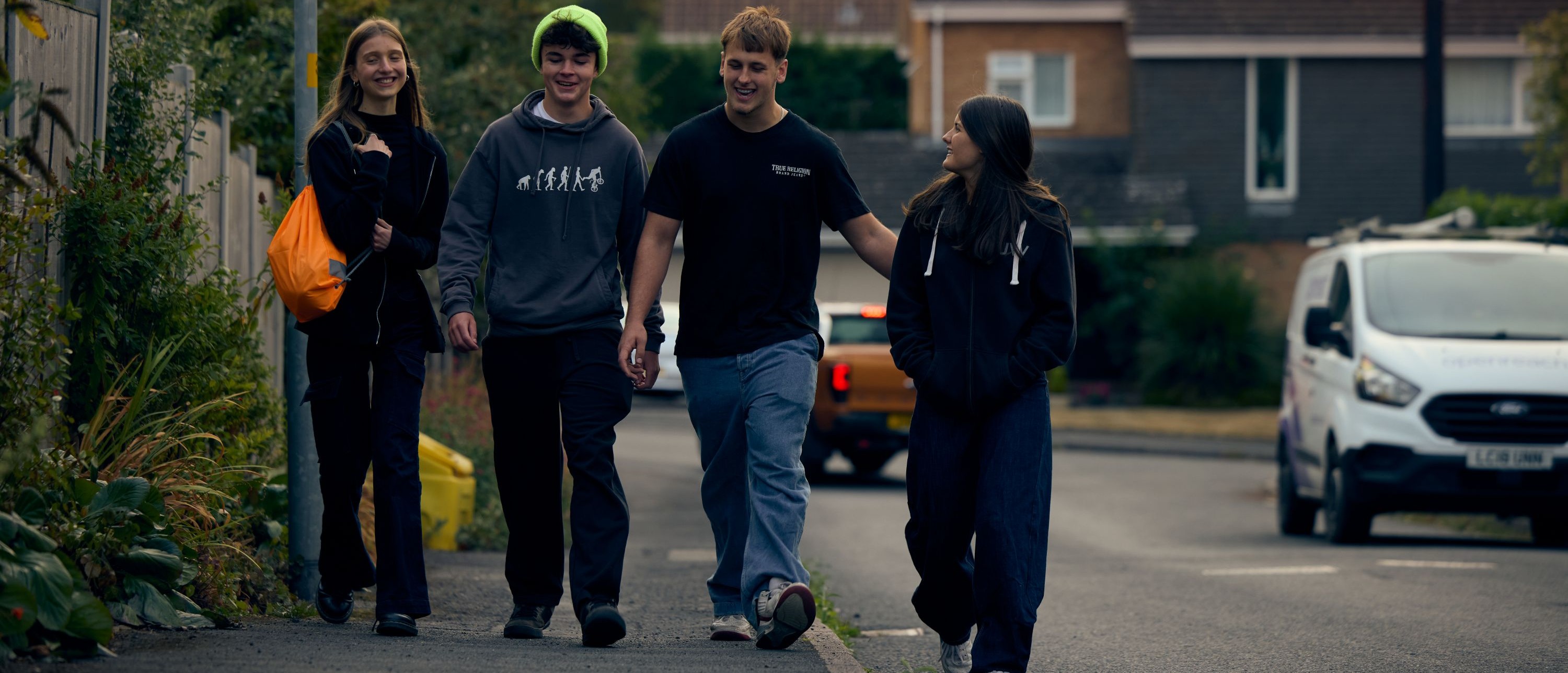 4 teenagers walking down the road talking and smiling