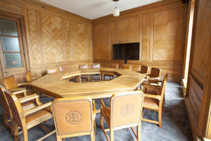 a wood panelled room with an octagonal wood table and leather chairs