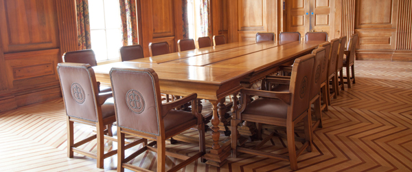 a wood panelled room with a long wooden table and leather chairs