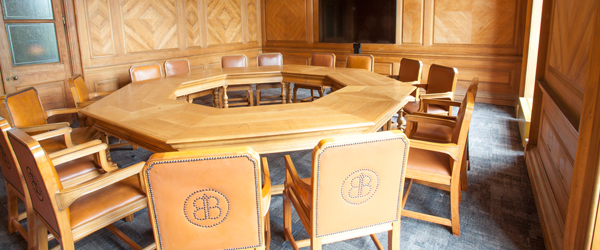 a wood panelled room with an octagonal wooden table and leather chairs
