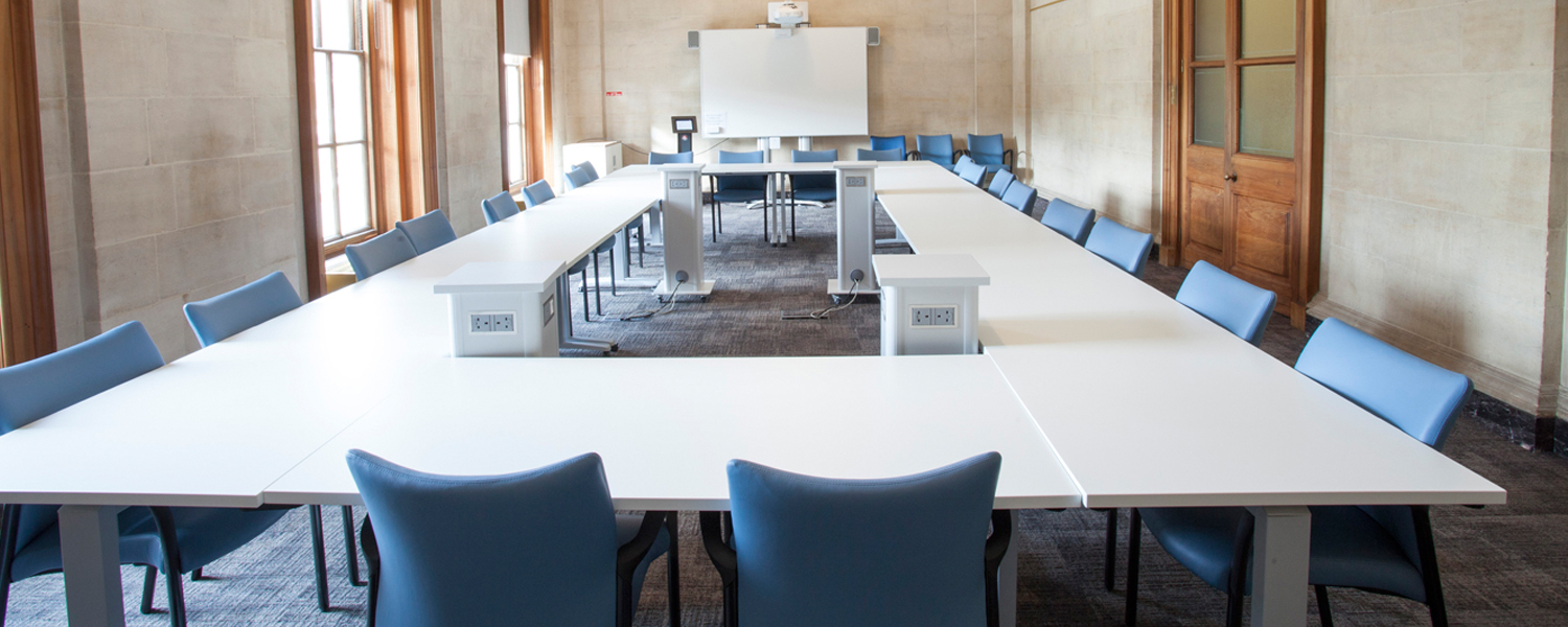 a spacious meeting room with a large rectangular white table and blue chairs