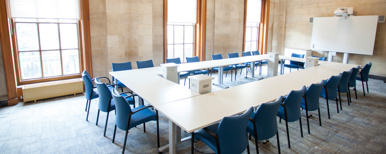 a spacious meeting room with a large rectangular white table and blue chairs