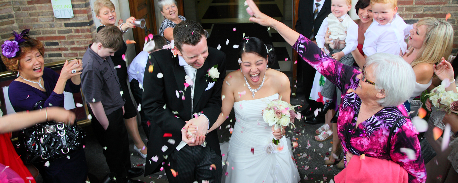 A bride and groom surrounded by guests showering them with confetti