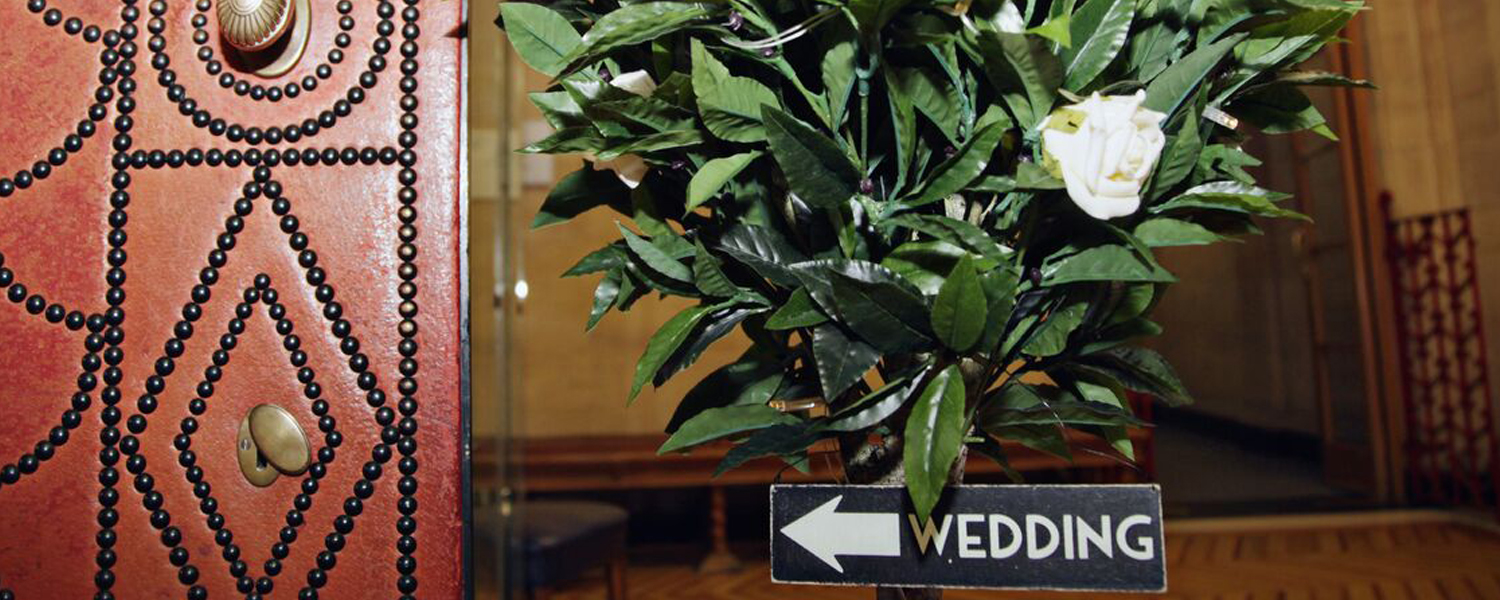 a leather studded door with a rosebush next to it and a sign saying wedding with an arrow pointing left