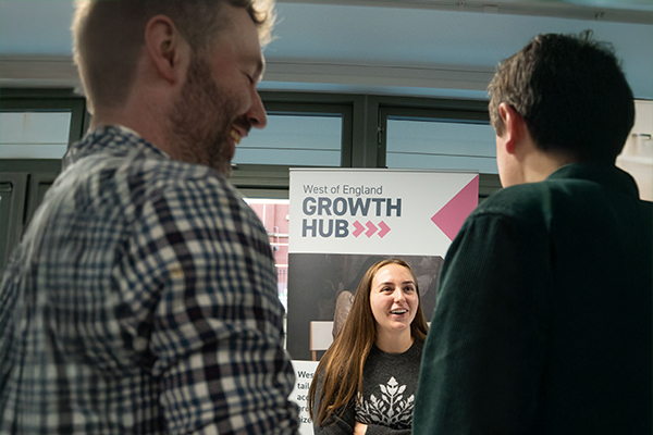 A woman talks to 2 men about the West of England Growth Hub at a business conference