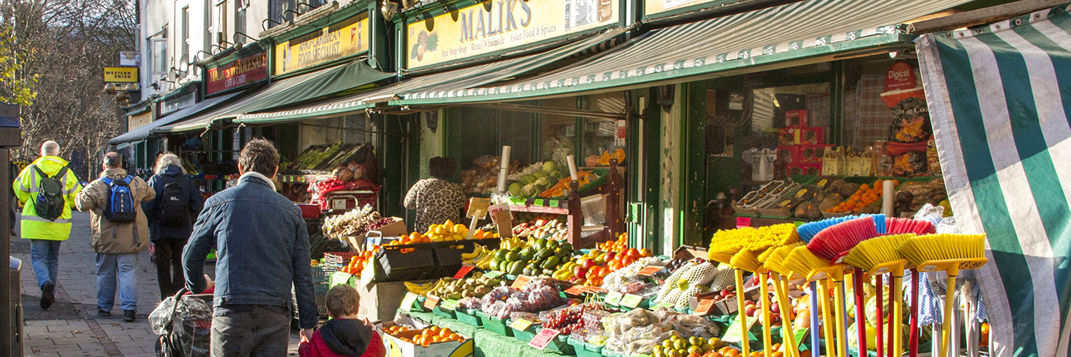 People walking past the outside of a local grocery in the Lawrence Hill district of Bristol