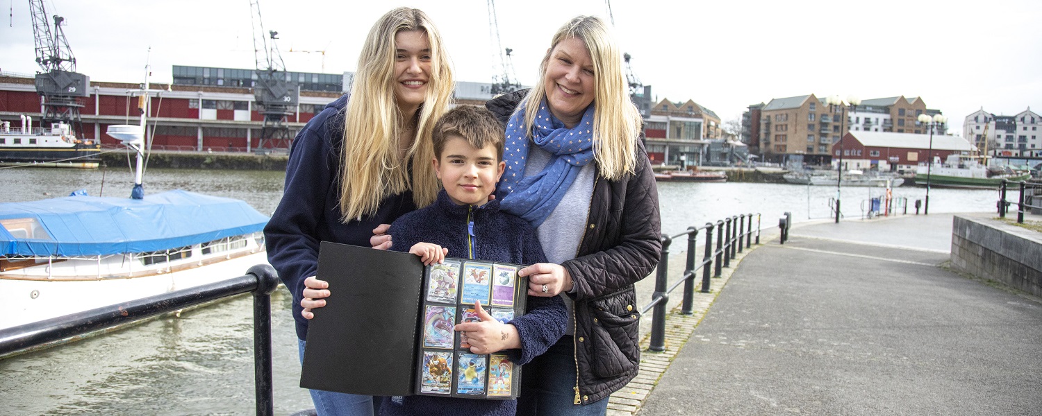 A woman, a teenage girl and a young boy holding a sticker album