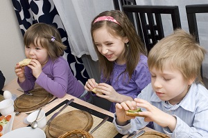 Three young children having breakfast at a table