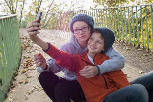 Two young adults hugging and taking a selfie