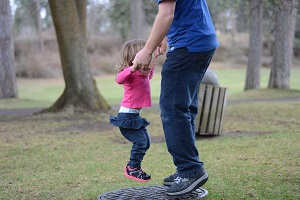 A man an a young toddler holding hands and jumping in the air