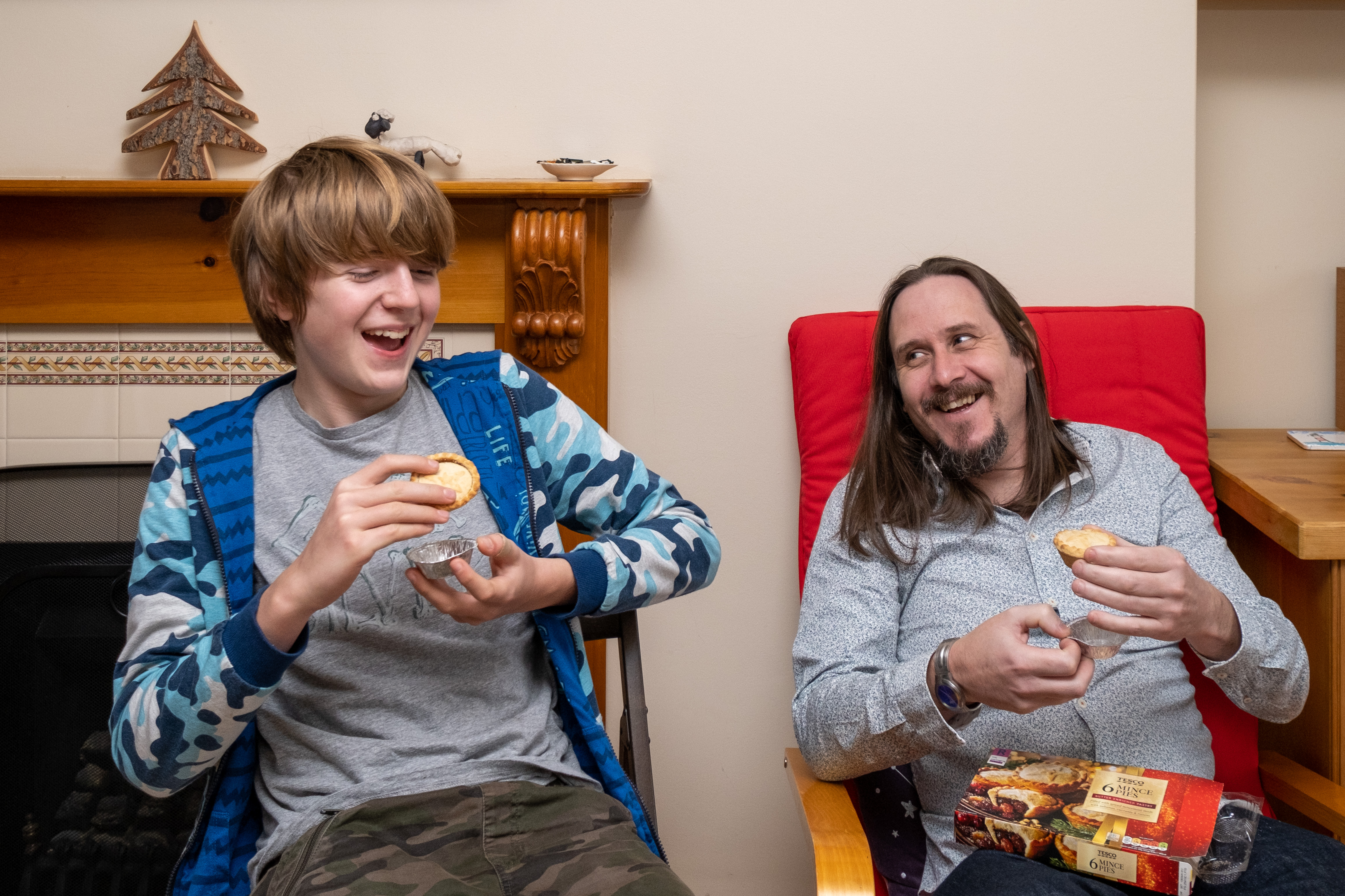 Man and teenage boy eating mince pies and laughing