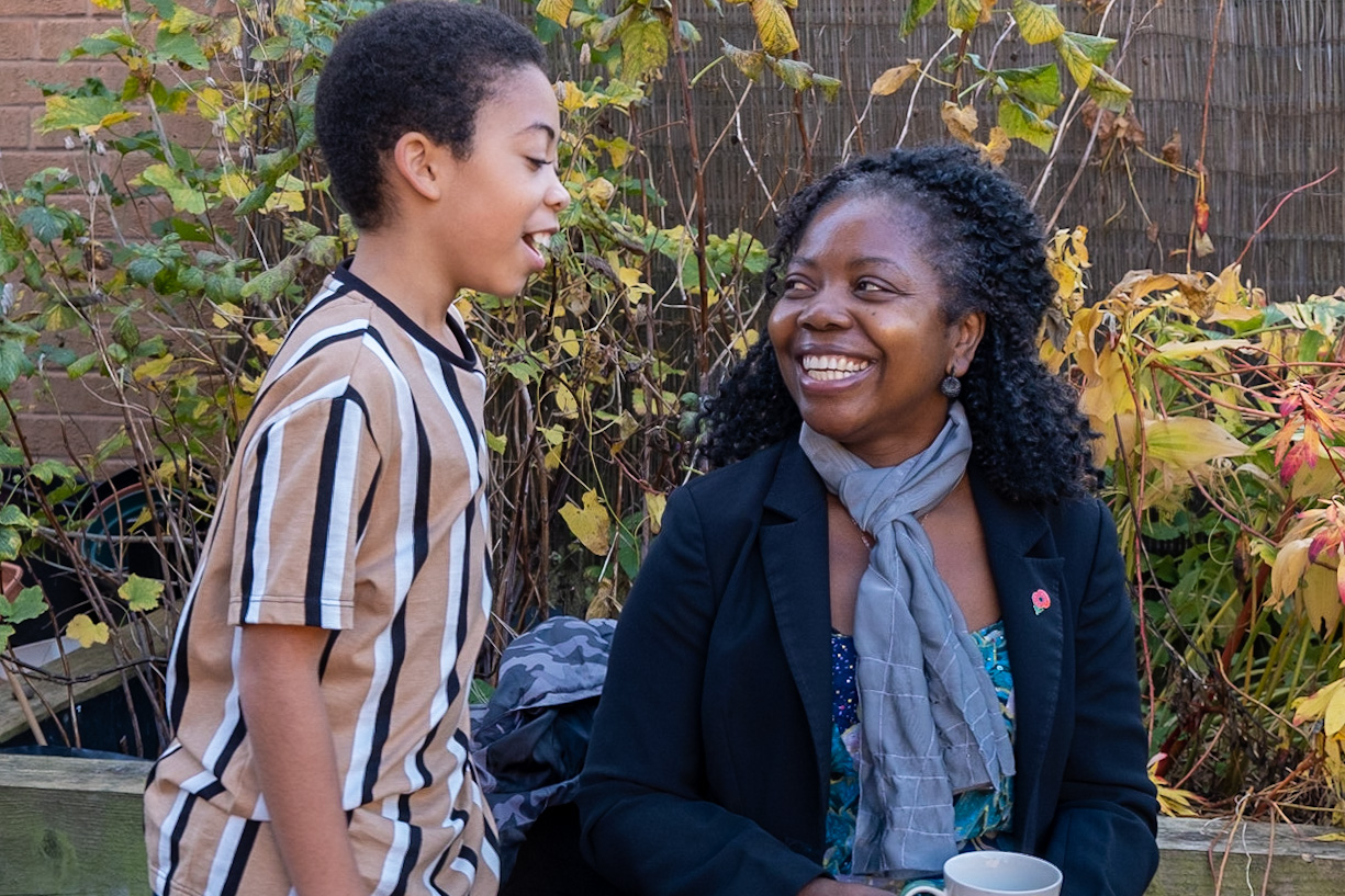 An adult woman and a young boy smiling at each other