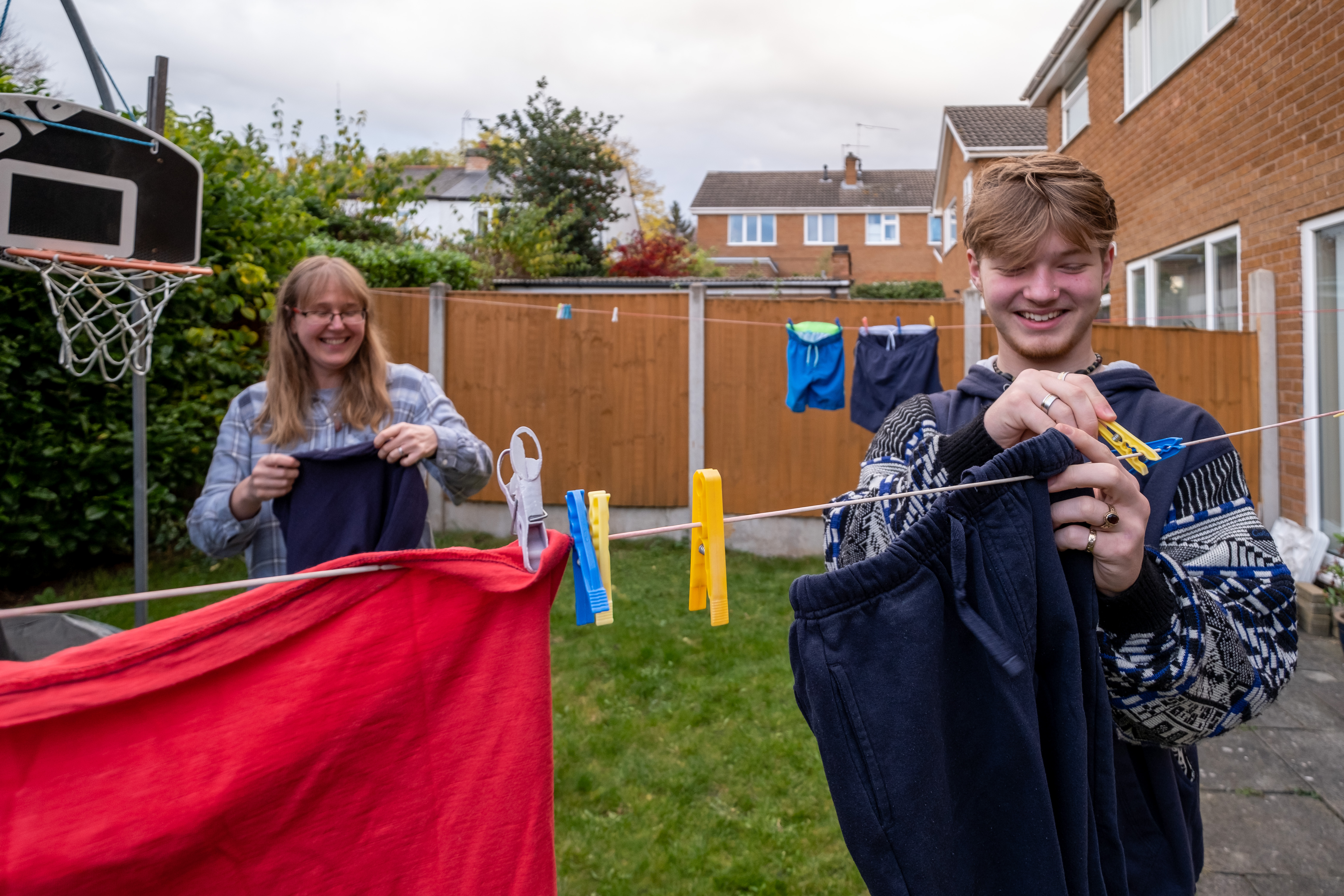 Woman and teenage boy hanging washing out in a garden