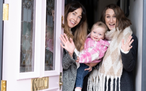 Two women and a baby opening front door