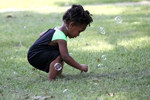 A young girl crouching on the grass