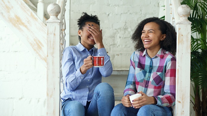 Two young women drinking tea and laughing
