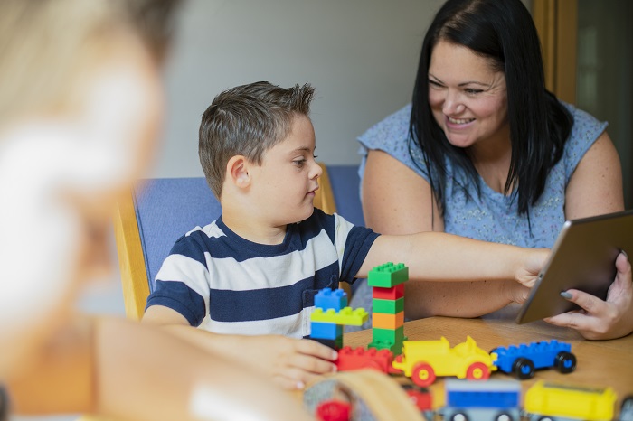 Woman and child playing with building blocks and a tablet