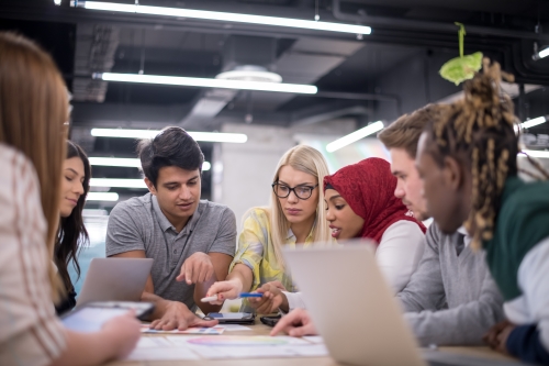 Diverse group of people having a team meeting around a table with laptops