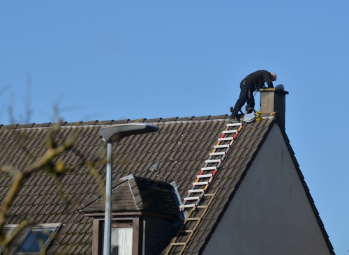 Man doing some repairs to a chimney on a roof