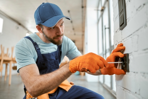 Man screwing a plug into a wall.