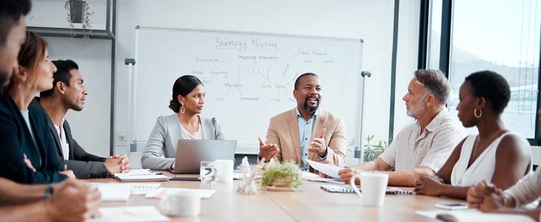 People in a meeting, gathered around a desk.