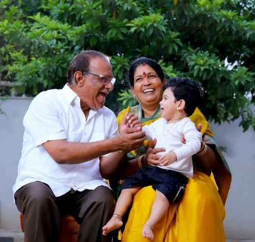 Carers with toddler laughing while sitting on a bench