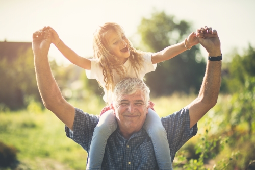 Elderly man holding his granddaughter on his shoulders