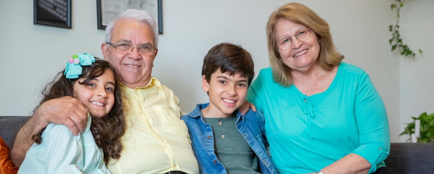 Older man and woman with young boy and girl smiling on a sofa