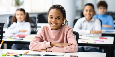 Schoolchildren smiling at desks in a classroom
