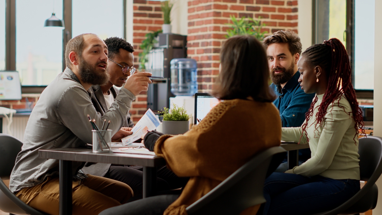 Group of male and female colleagues sat around a desk having a discussion