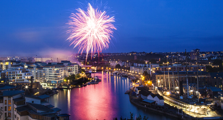 view of bristol floating harbour in the evening with pink fireworks in the sky