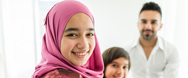 teenage Muslim girl with a young boy and a young man in the background