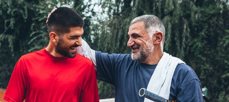 Two people looking happy and healthy on a clay tennis court.