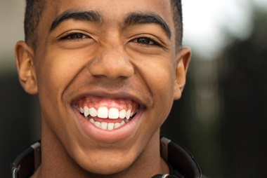 A young person with headphones around his neck, smiling. 