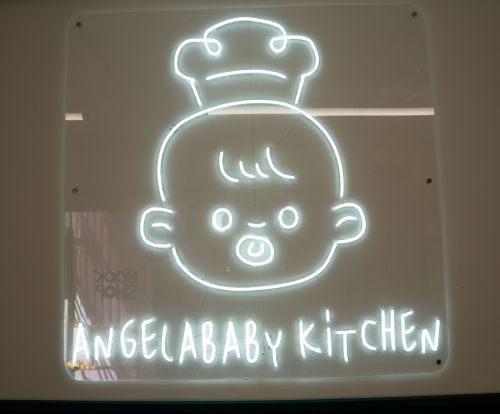 A luminous sign with a baby wearing a chef hat and words beneath it saying ANGELABABY KiTCHEN