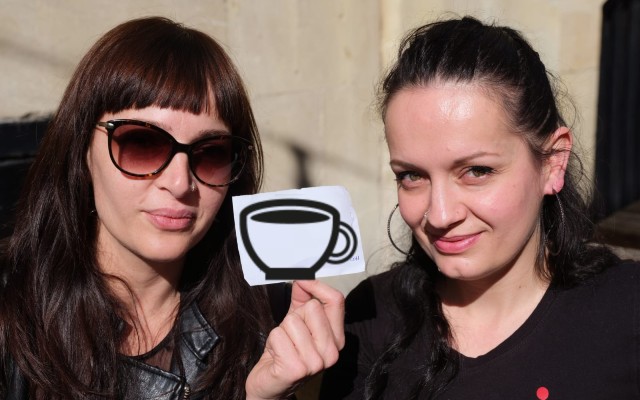Two ladies, one holding up a picture of a cup