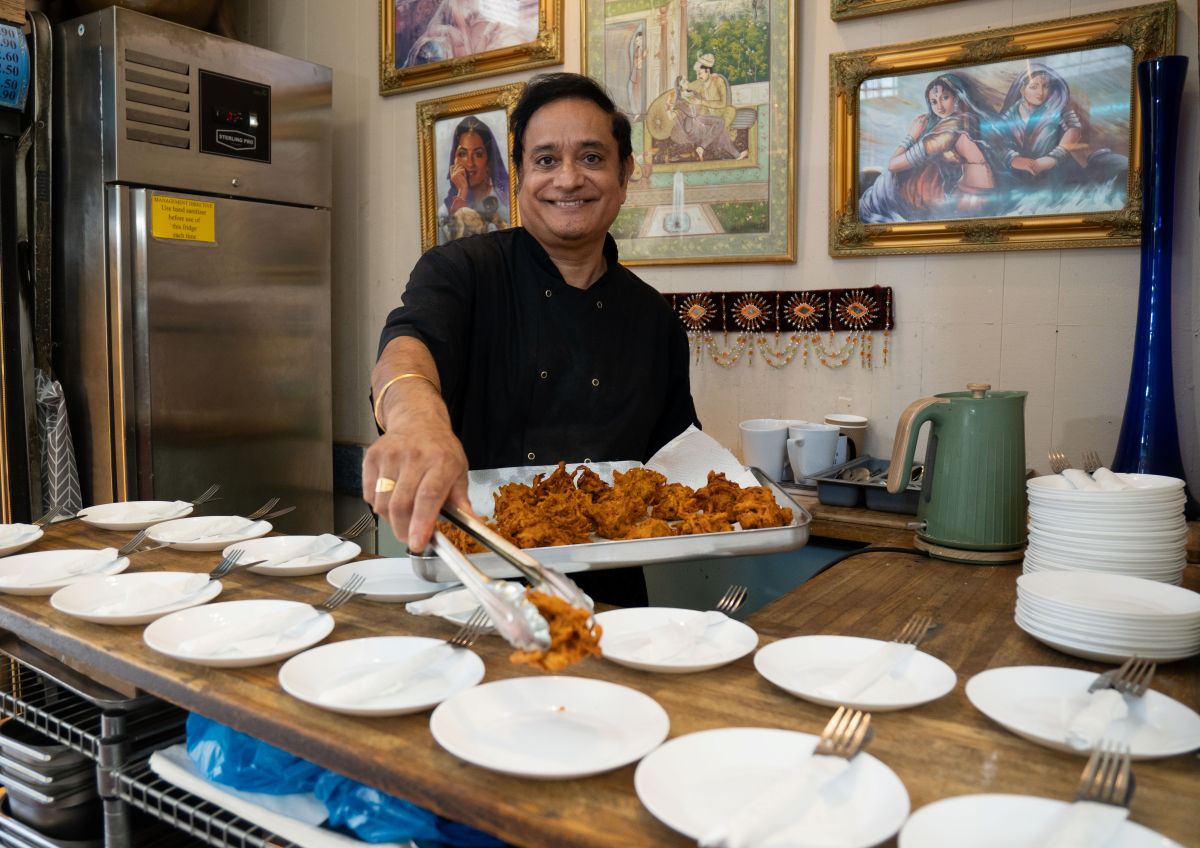 A smiling man putting food on some plates